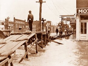 Picture of clapboard bridge over floodwaters on the corner of Walnut and Main. 